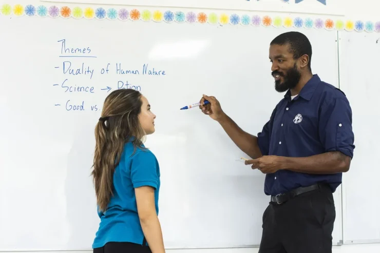 An MBS teacher and student discussing literature themes at the whiteboard