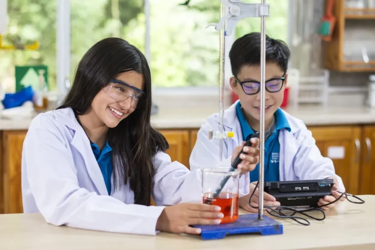 Two MBS students conducting a chemistry experiment with colored solutions